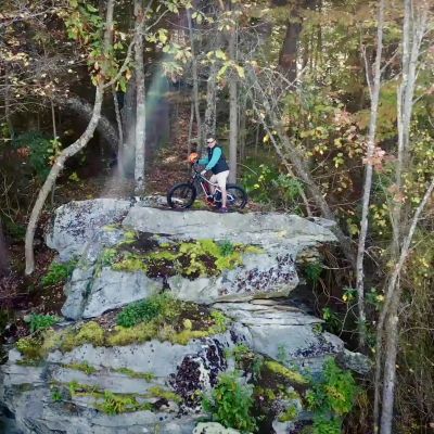 Podcast episode guest, Town Manager Steve Lawson, perched on a mountain bike at the top of a rocky outcrop overlooking the mountains and valley on an autumn day in Big Stone Gap, Virginia.