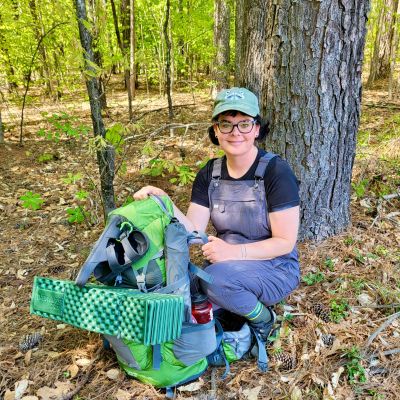 Ranger Amelia Hulth with her backpack while camping at a primitive campground.