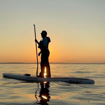 Podcast episode guest, Warren Veazey, paddling on a SUP on the Potomac River during sunset.