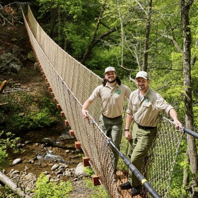 Rangers Daniel Flors and Ronnie Hylton standing on a brand new swinging bridge at Breaks Park. The bridge is one of several new trail development at the Breaks.