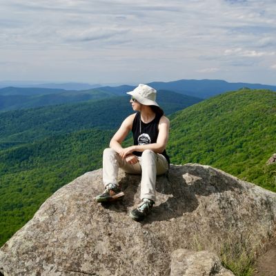 Podcast Host, Jessica Bowser, sits on rocky outcrop in Shenandoah National Park